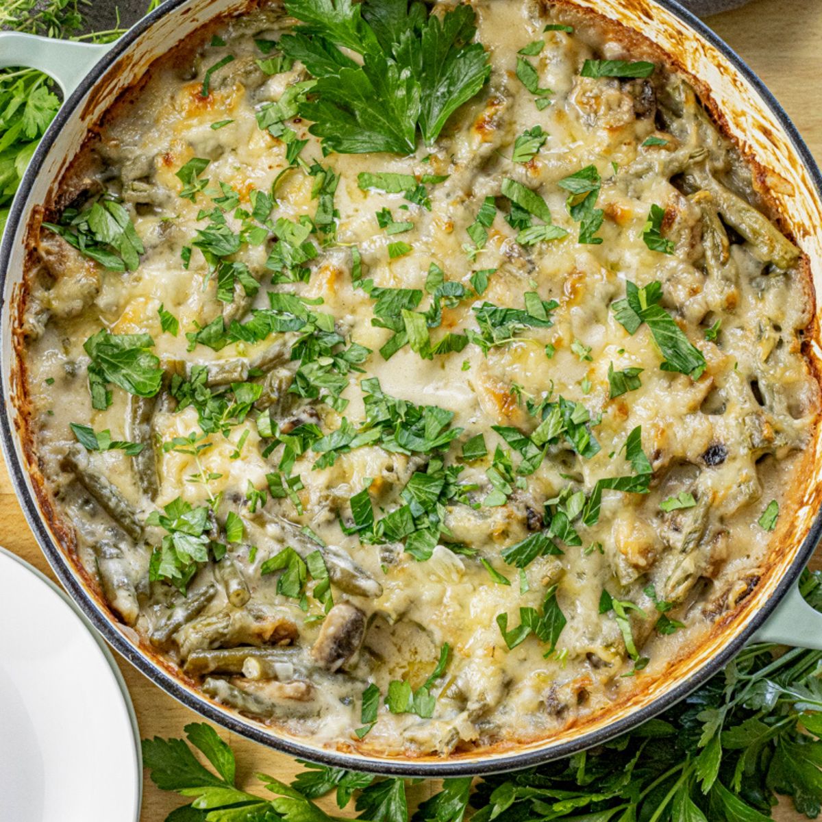 green bean casserole with melted swiss cheese baked in a large enameled skillet