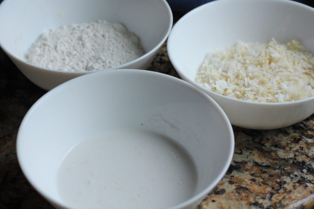 3 bowl used to make coconut shrimp. One with coconut milk, an other with flour and lastly panko and coconut flakes.
