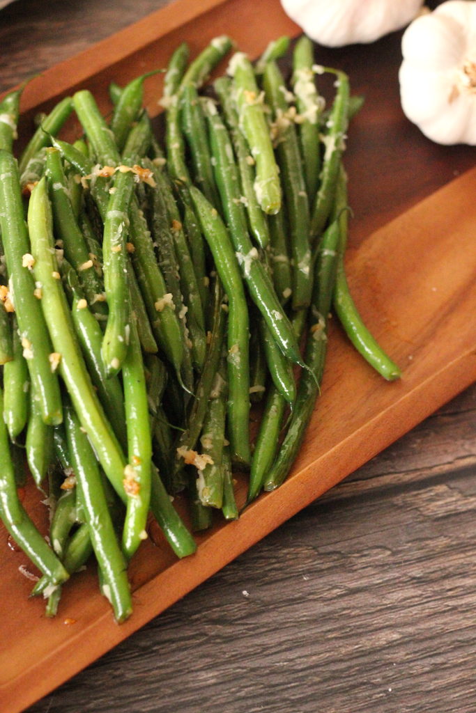 Garlic Parmesan Green Beans are a simple and delicious side dish that go perfect with whatever you've got on the dinner menu! Garlic Parmesan Green Beans cooked on a wooden platter
