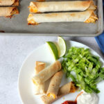 Crispy oven baked chicken taquitos served on a plate with salsa and sour cream