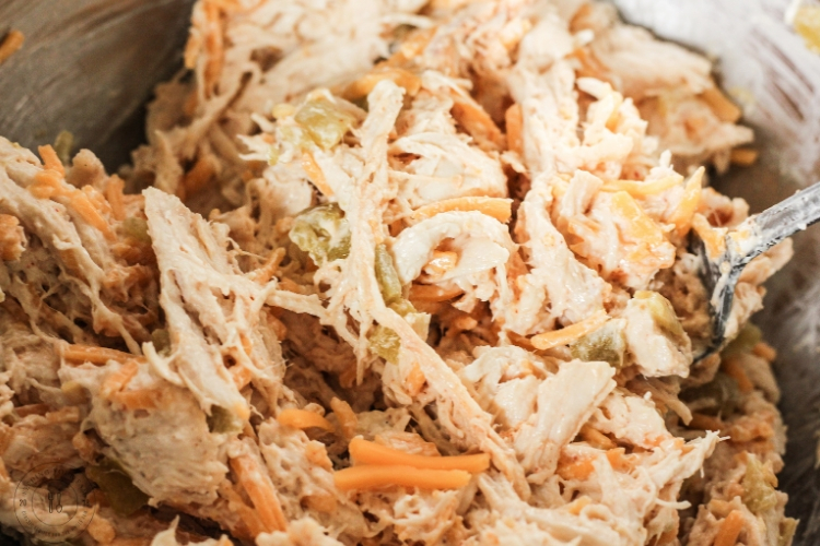 Creamy chicken taquito filling mixed in a glass bowl with shredded chicken, cheese, and cream cheese