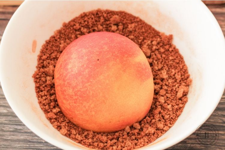 slice peach cut side down in a bowl of brown sugar and cinnamon