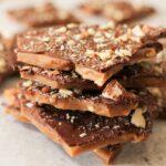 pile of english toffee topped with chocolate and chopped nuts