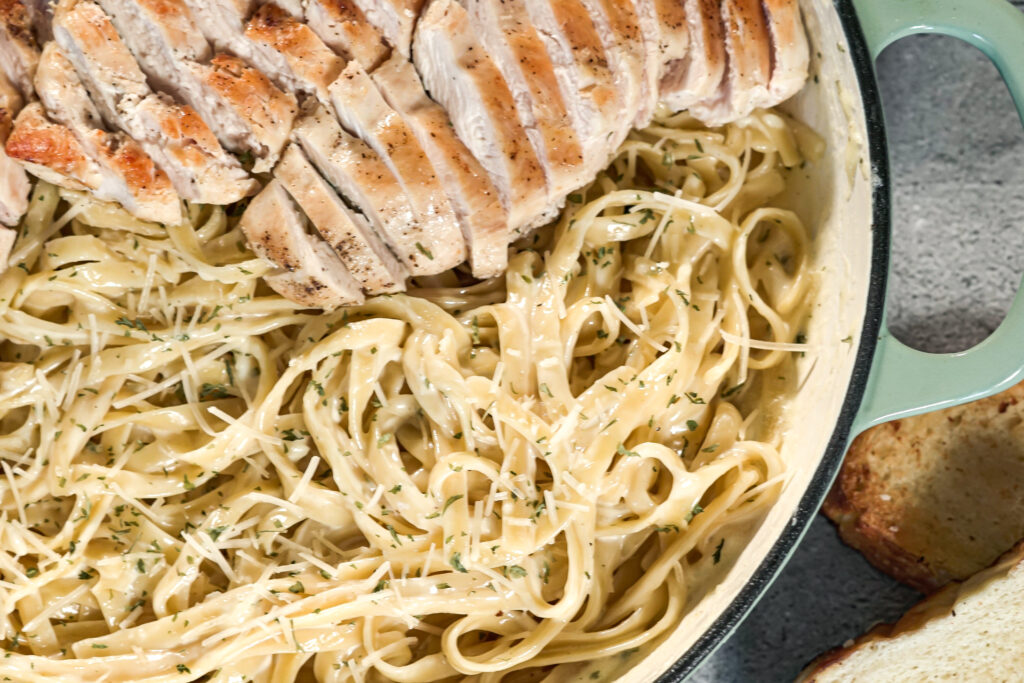 pan of asiago cheese alfredo with sliced chicken