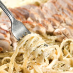fork lifting asiago alfredo out of a pan