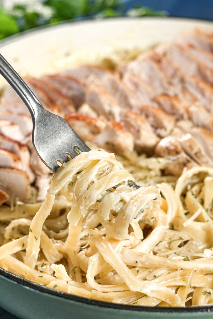 fork lifting asiago alfredo out of a pan