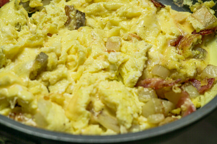 scrambled eggs and bacon in a skillet