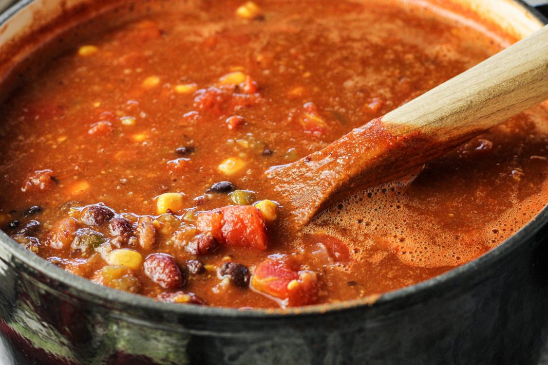 wooden spoon scooping soup from a pot to make 8 can taco soup recipe