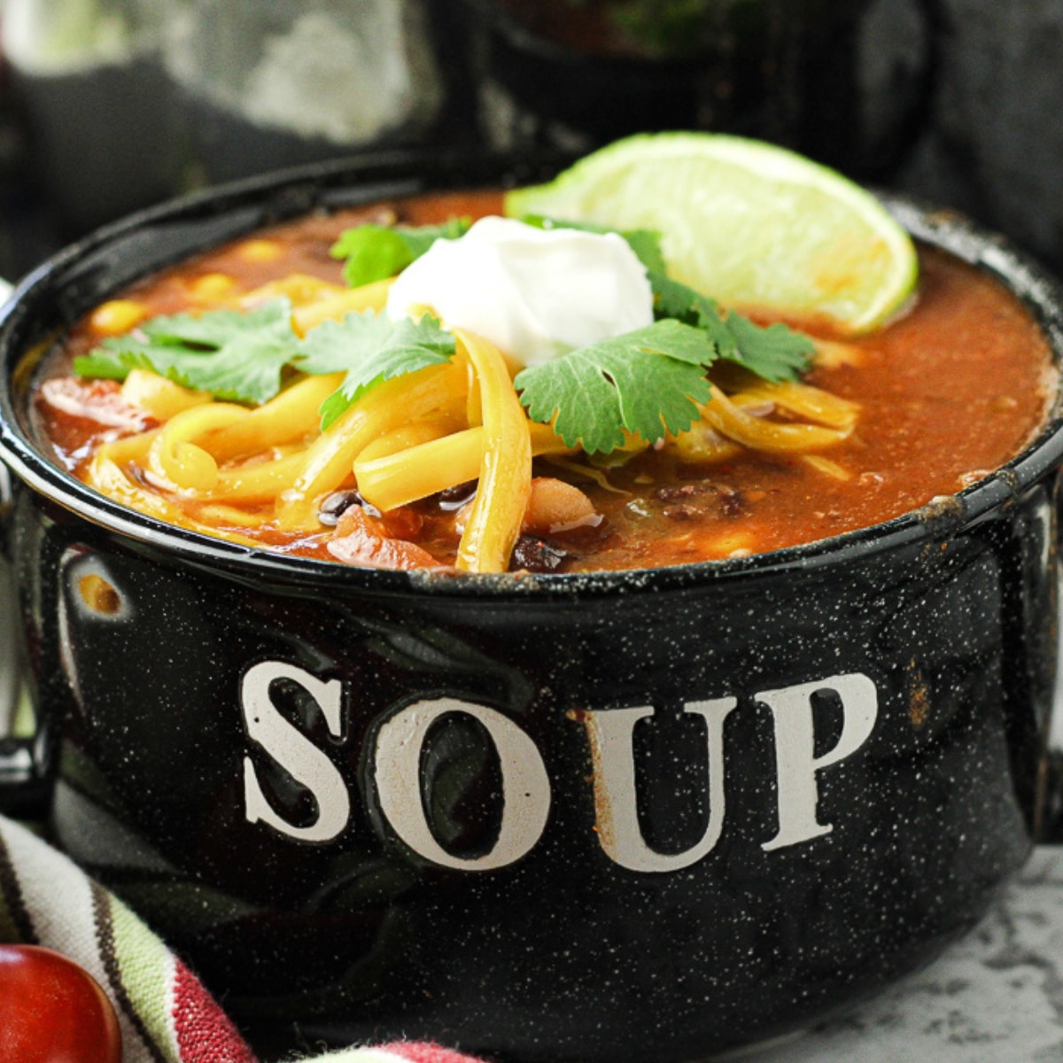 taco soup recipe in a bowl labeled soup, topped with sour cream, cheese and cilantro