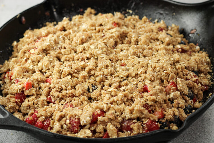 crumble topping over mixed berries in a cast iron pan
