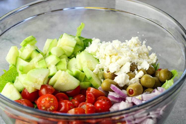 sliced tomatoes, cucumbers, onions, feta cheese, green onions on romaine lettuce