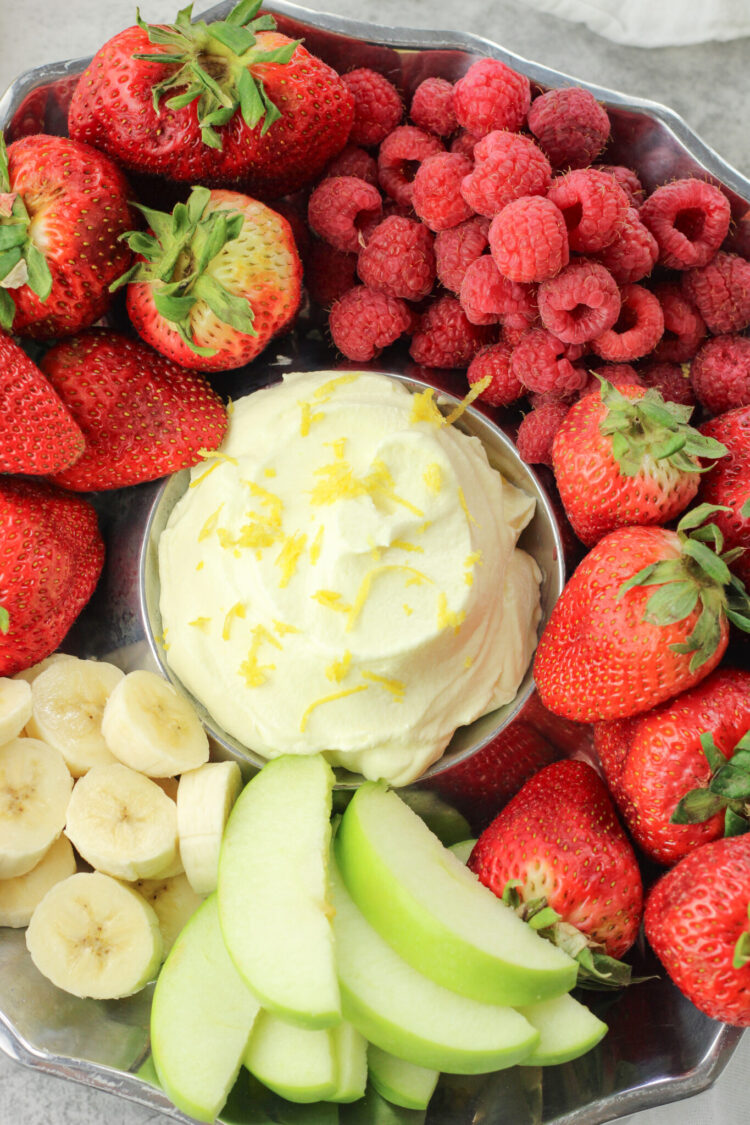 bananas, strawberries, raspberries and green apples surrounding yellow lemon fruit dip in the center