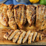 chicken breasts, one sliced on a wooden platter