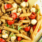 penne pasta salad with mozzarella pearls, tomatoes and basil in a balsamic dressing