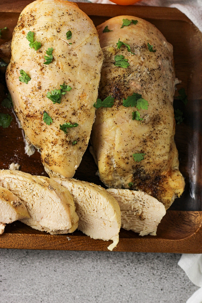 oven baked chicken breasts with some sliced pieces on a wooden serving platter
