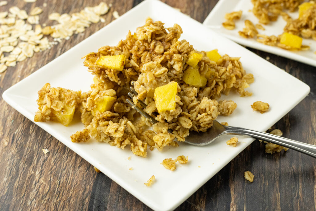 baked oatmeal with peaches on a white plate with a fork