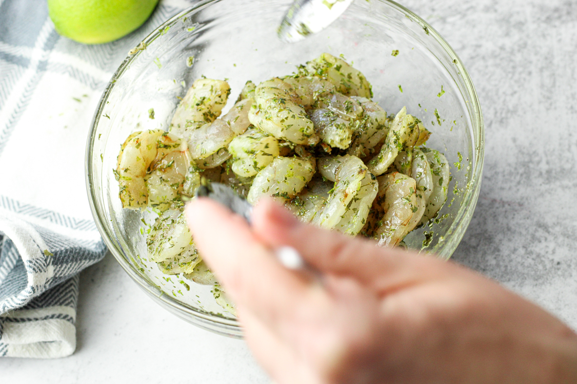 combining shrimp with lime and spices in a small glass bowl