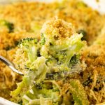 spoonful of creamy broccoli casserole from a white casserole dish