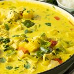 big pan of pineapple curry with green peppers, onions, chicken, red peppers and pineapple in a yellow curry sauce