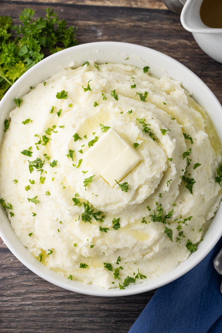 big bowl of mashed potatoes topped with butter and parsley