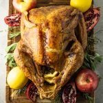 baked turkey surrounded by lemons, pomegranates, spices and apples