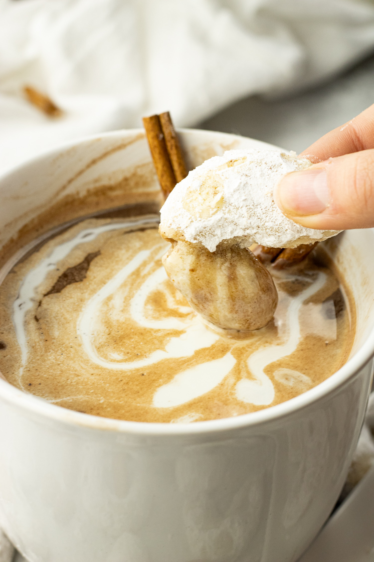 dipping powdered sugar coated cookies into hot chocolate