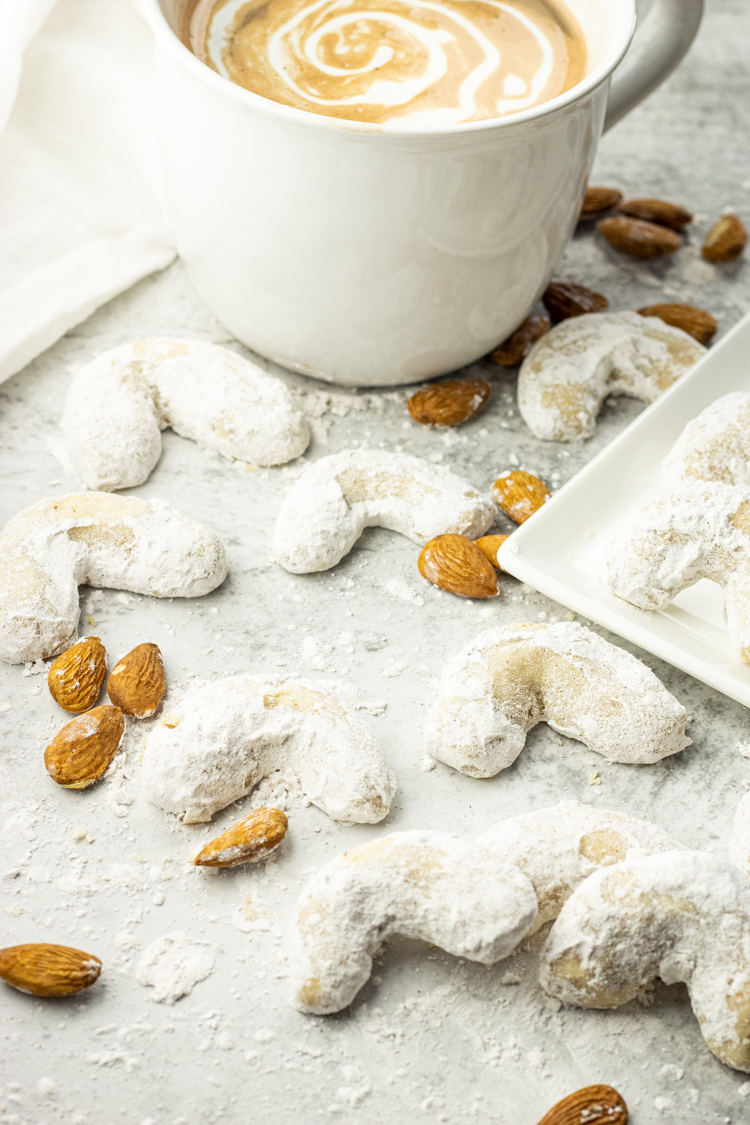 cup of cocoa with powdered sugar dusted crescent cookies around