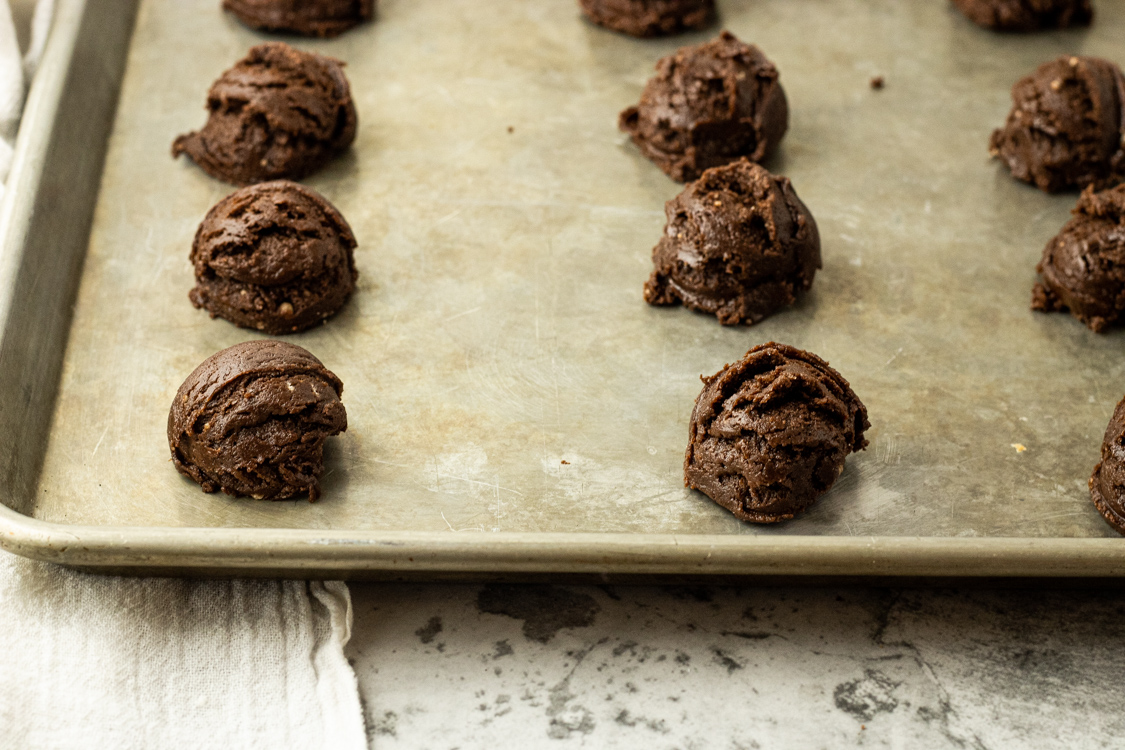 chocolate dough balls on a baking sheet
