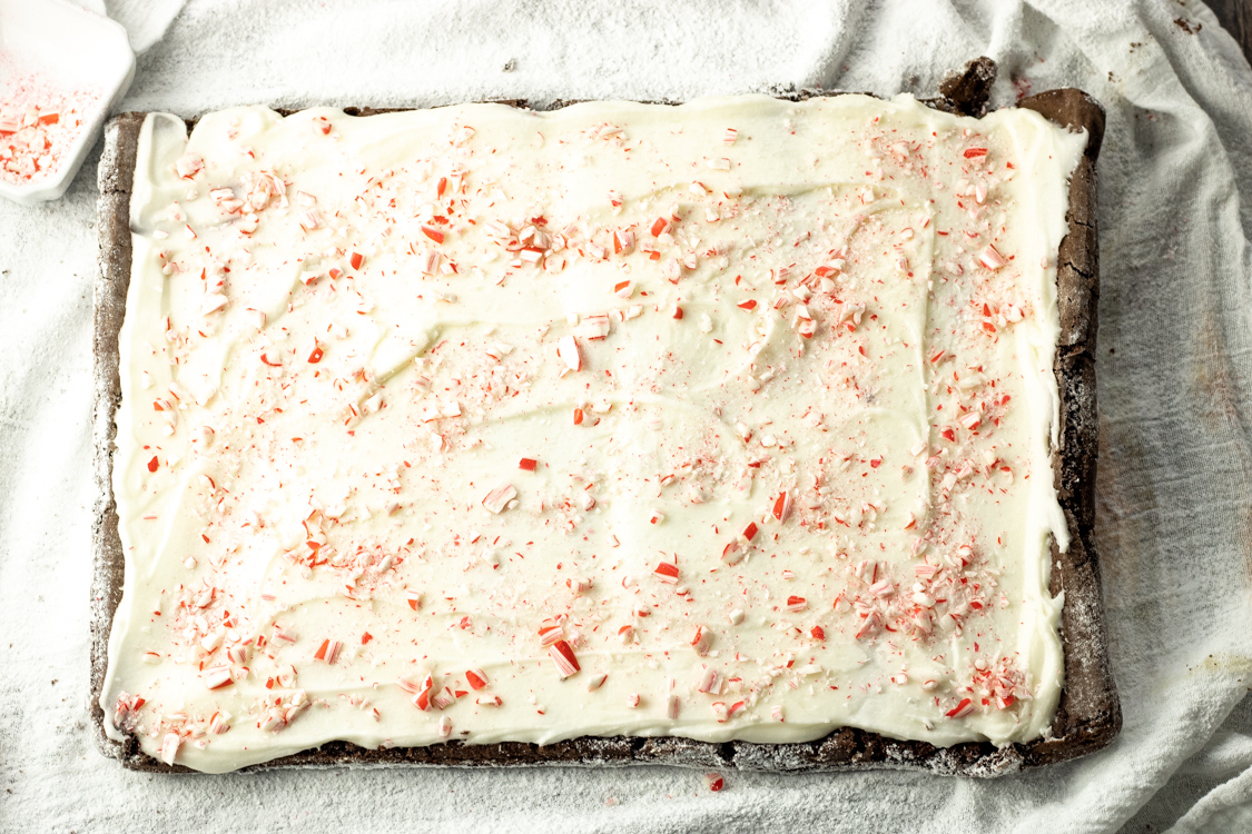 frosting rolled cake with white frosting topped with crushed candy canes