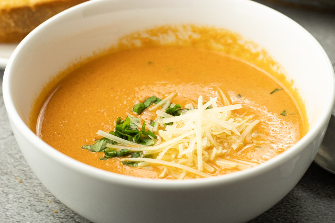soup made from tomatoes topped with parmesan cheese and basil