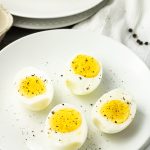 hard boiled eggs that have been cooked in an air fryer, sliced in half on a white plate