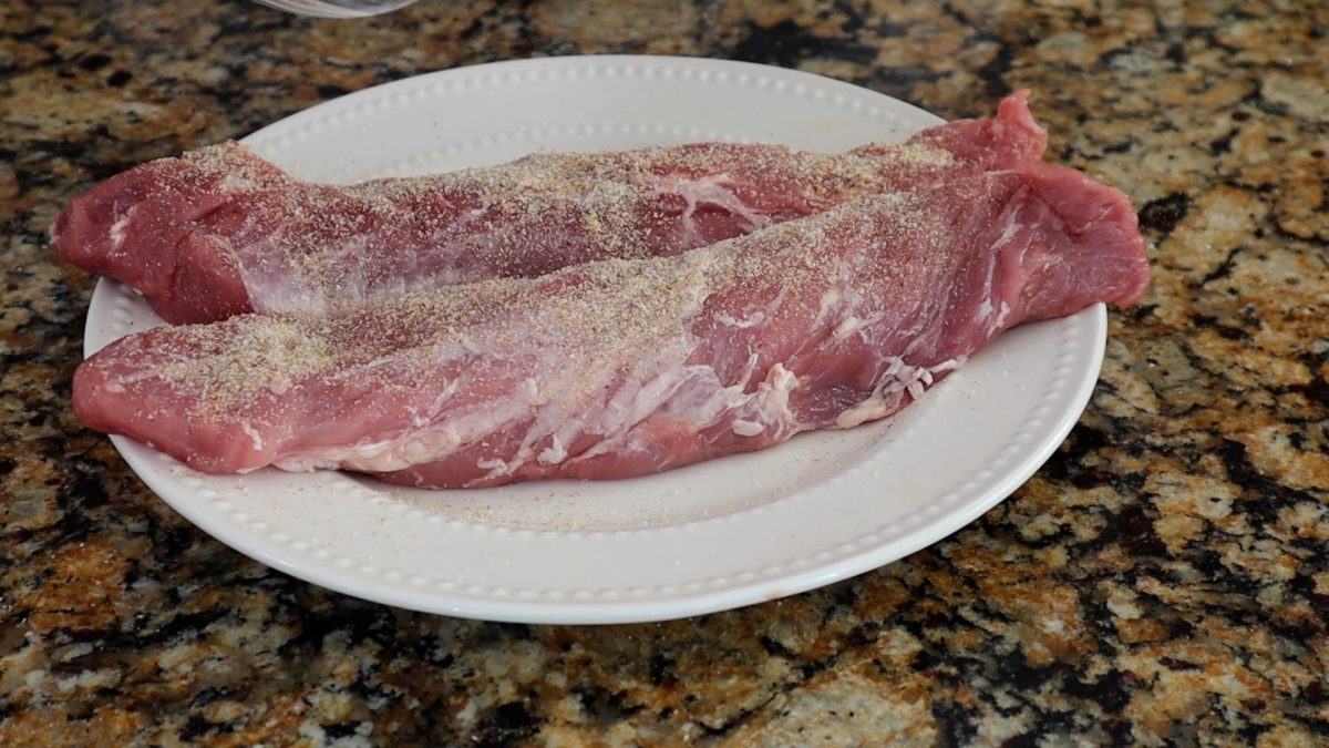 pork tenderloins seasoned on a white plate