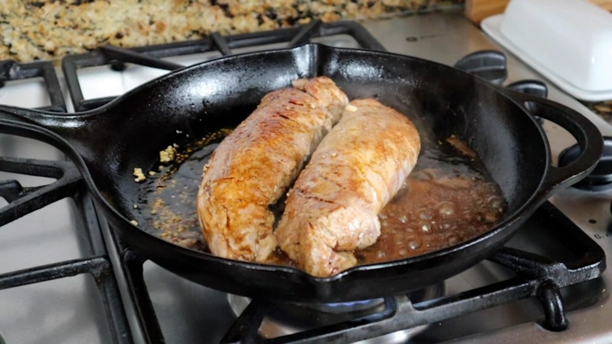 browning pork tenderloins in a cast iron pan