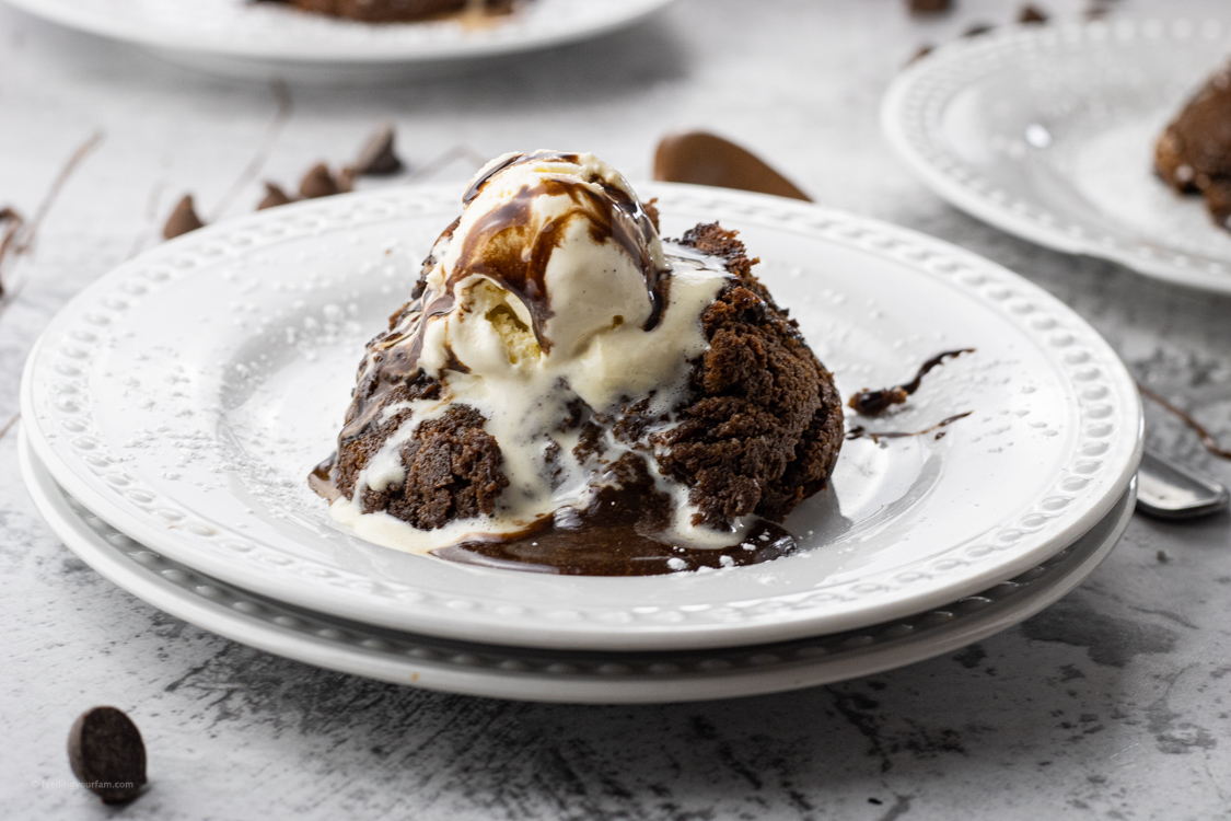 chocolate spilling out of a small chocolate cake topped with ice cream