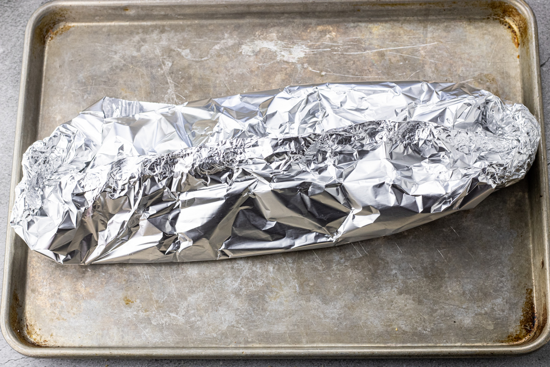salmon wrapped in foil on a baking sheet
