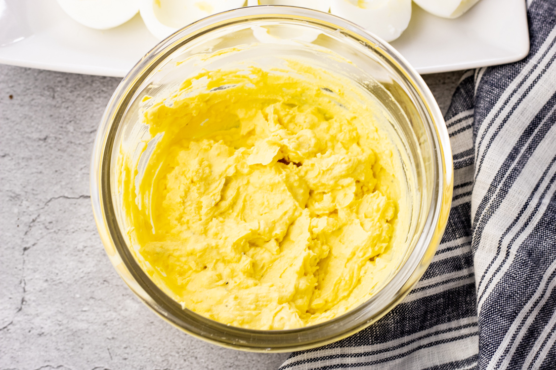 mixture for deviled egg in a glass mixing bowl