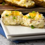 twice baked potato sliced in half on a white plate