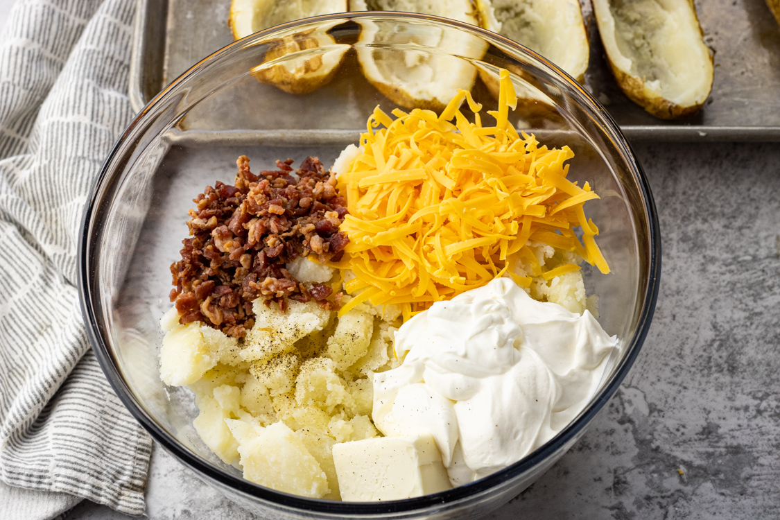 bowl with potatoes, cheese, butter, sour cream and bacon