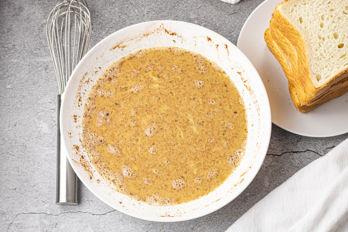 bowl of whisked eggs with milk and spices