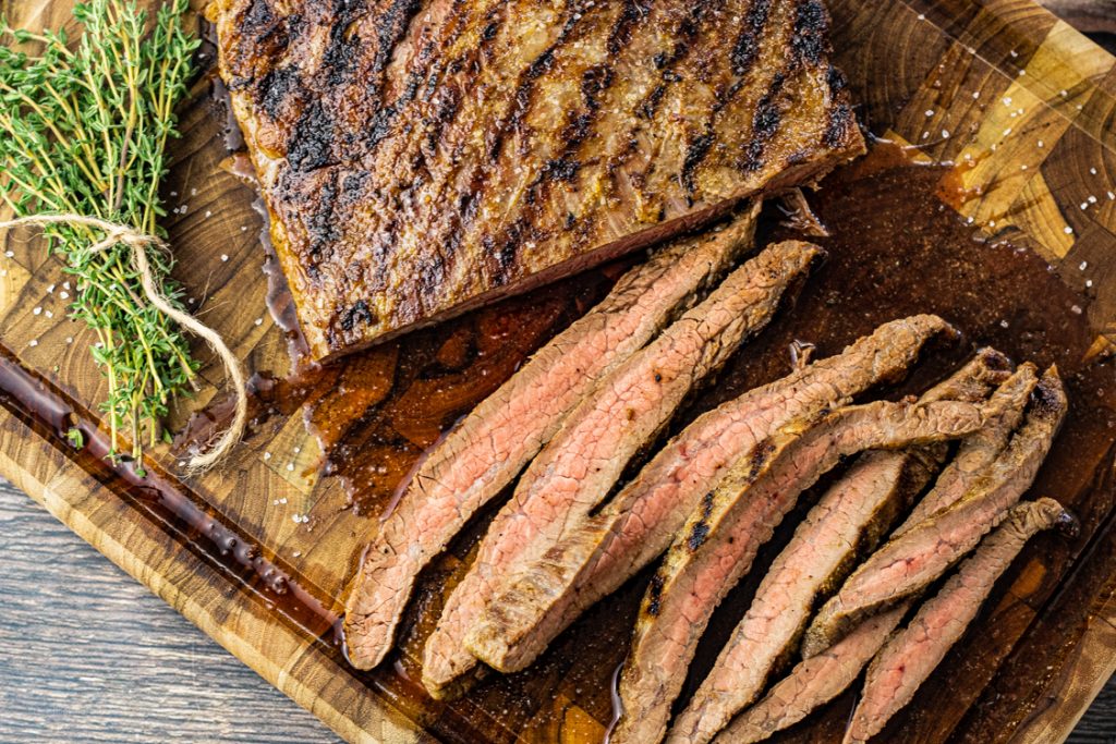 slice flank steak on a wooden cutting board