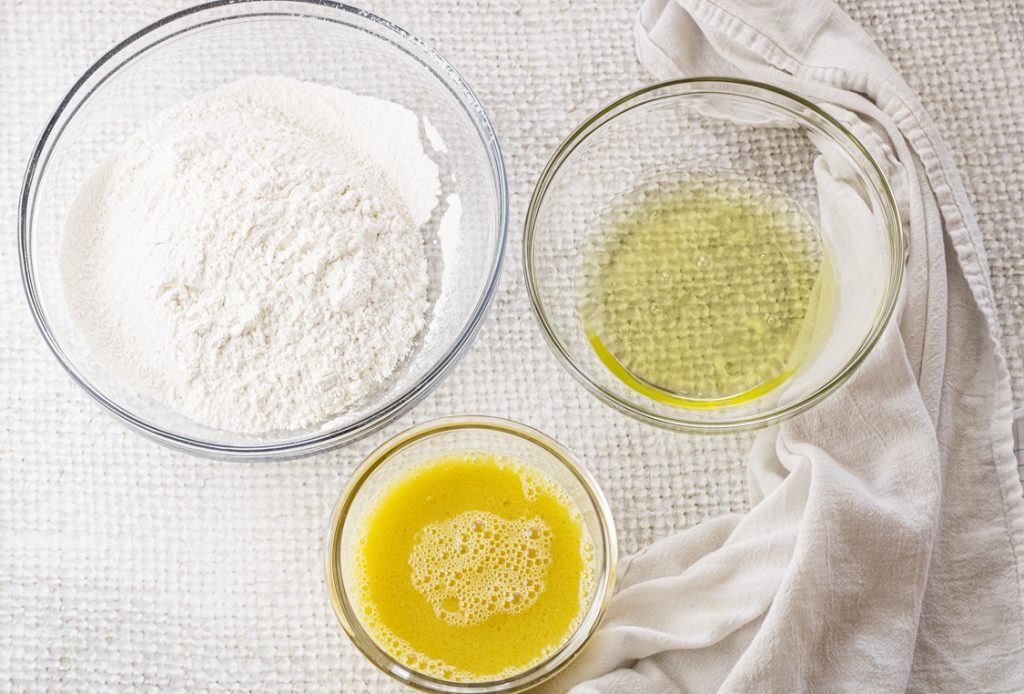 3 glass bowls. One with flour, one with egg whites and another with egg yolks