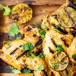 pieces of grilled chicken thighd on a wooden platter