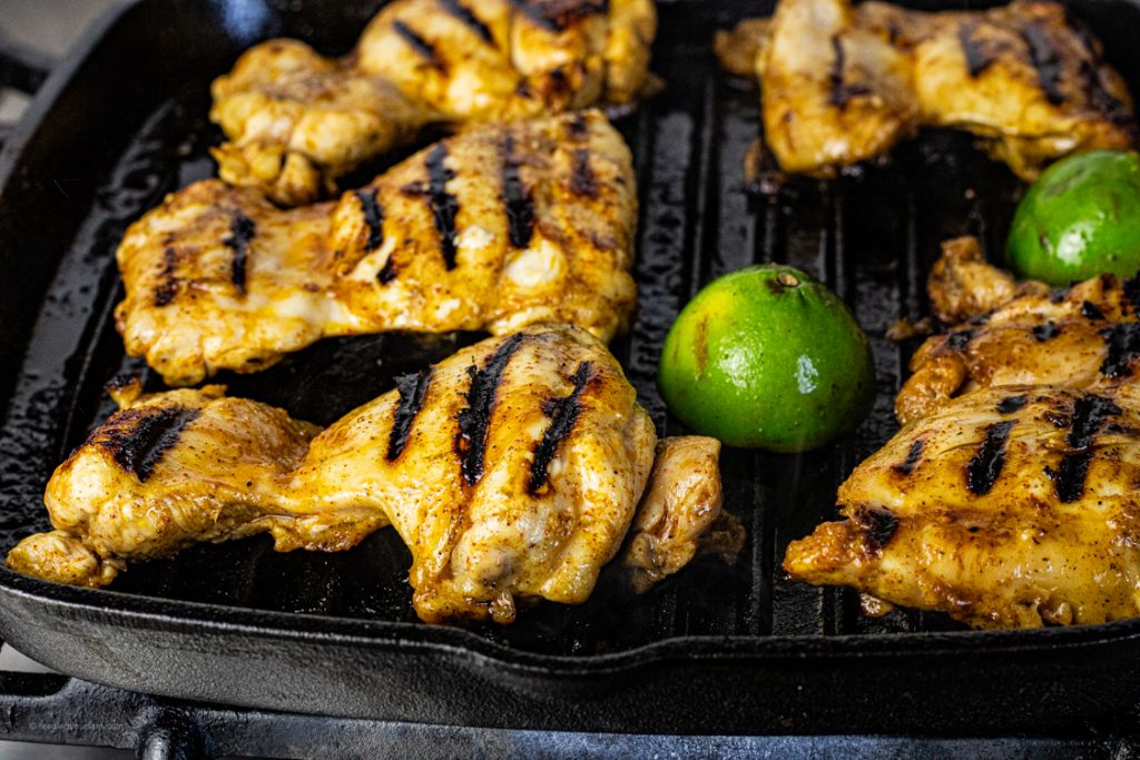 chicken thighs grilling on a cast iron grill pan