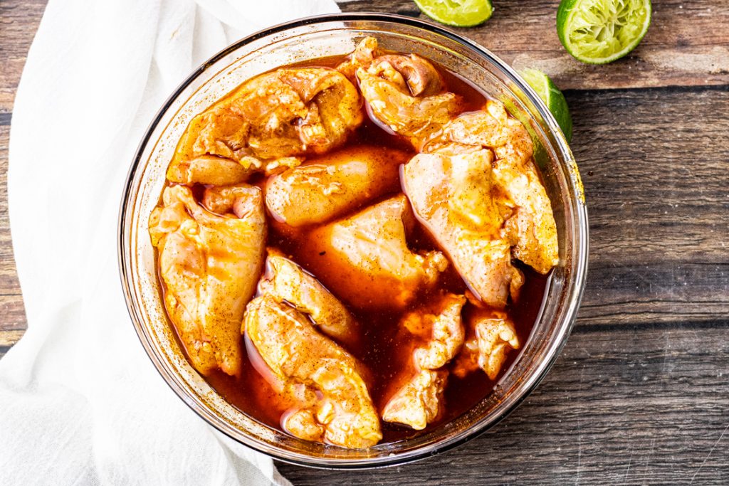 chicken thighs marinating in a bowl with a lime and chili marinade