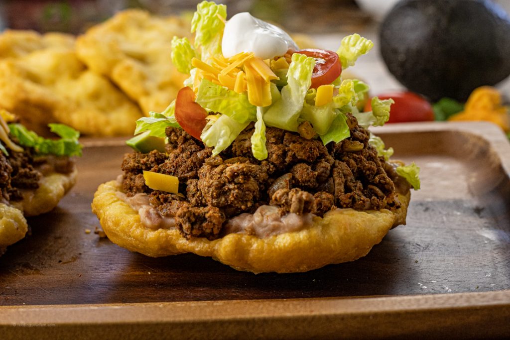 scones topped with taco meat, lettuce, cheese, tomatoes and sour cream
