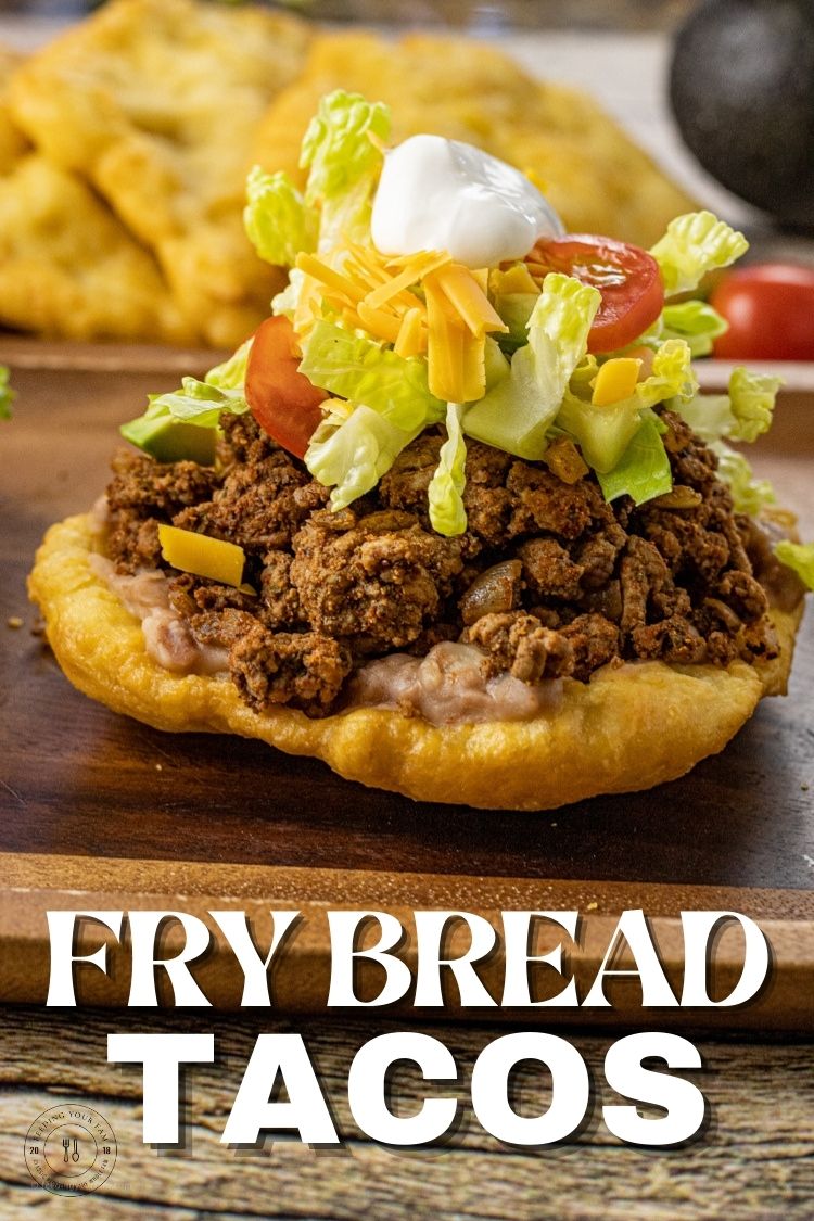 A simple Fry Bread made of a crispy outside and soft, chewy center is topped with refried beans, taco meat, lettuce, salsa, sour cream and all your favorite toppings to make this easy recipe for Fry Bread Tacos. This Fry Bread Taco Recipe will soon be on repeat on the family meal plan.