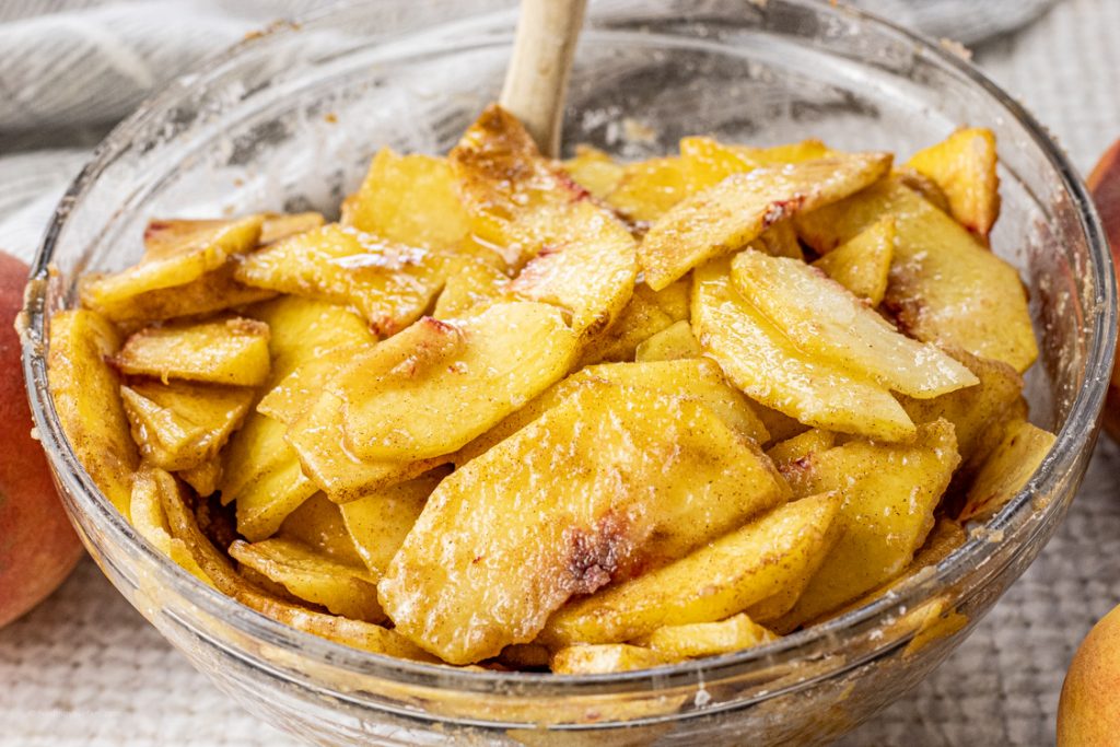 peeled and sliced peaches in a glass mixing bowl