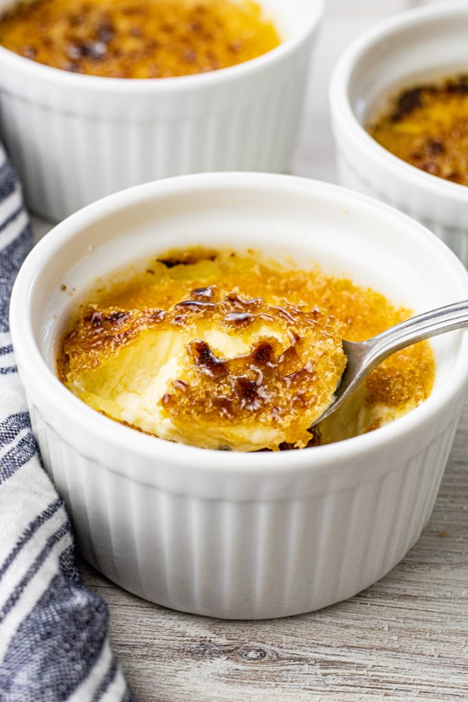 Spooning out of a small white ramekin some custard
