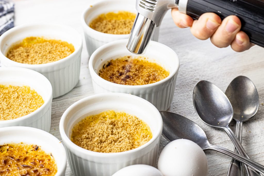 torching sugar on top of small ramekins of creme brulee