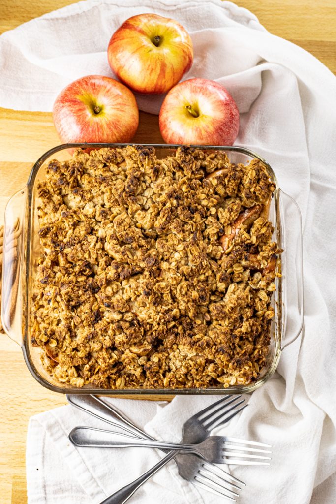 square pan of crunchy oat topping on apples for apple crisp